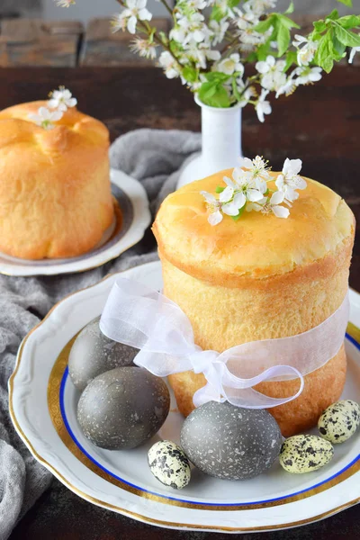 Buona Pasqua concetto. Pane dolce con frutta secca e uova colorate. Colazione festiva. Kulich ortodosso. Posto tavola festivo decorazione con paska, ramoscelli di fiori . — Foto Stock