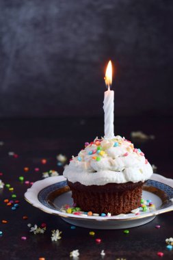 Vanilyalı krema ve mum ile çikolatalı kek. Doğum günün kutlu olsun. Karanlık fotoğraf.