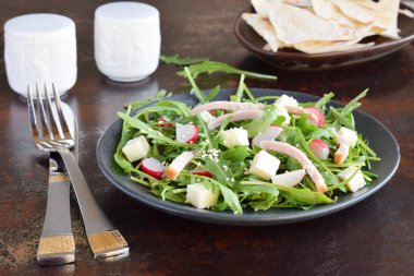 Salata taze sebze - roka, turp, beyaz peynir ile düz ekmek tortilla siyah plaka. Sağlıklı gıda