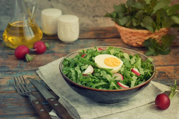 Vitaminsalat aus Salat, Rettich, grünen Zwiebeln und Eiern, gewürzt mit Pflanzenöl im Teller auf Holzgrund. Gesunde Ernährung. Salat mit frischem grünen Gemüse — Stockfoto