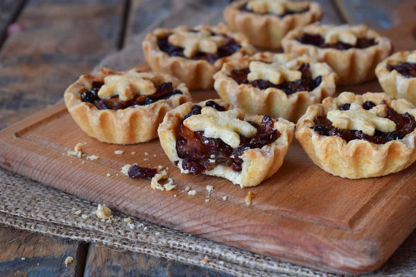Mini Ταρτάκια με αποξηραμένα φρούτα και ξηρούς καρπούς. Μπισκότα κουλουρακιών με φρούτα γέμισμα σε ξύλινα φόντο. Μικρό γλυκό πίτα. Χώρο αντίγραφο. — Φωτογραφία Αρχείου