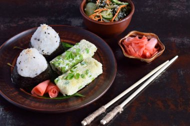 Japon yemekleri - pirinç topları onigiri, omlet, turşu zencefil, sunomono wakame salatalık salatası ve yemek çubukları karışımı. Kahvaltı ve öğle yemeği arka plan