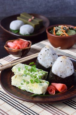 Japon yemekleri - pirinç topları onigiri, omlet, zencefil, sunomono wakame salatalık salatası karışımı. Fasulye ve yeşil çay matcha - jöle yokan, daifuku mochi geleneksel tatlı. Asya kahvaltı ve öğle yemeği