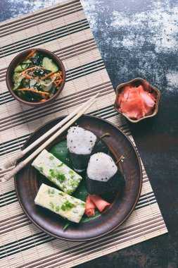 Japon yemekleri - pirinç topları onigiri, omlet, turşu zencefil, sunomono wakame salatalık salatası ve yemek çubukları karışımı. Kahvaltı ve öğle yemeği arka plan