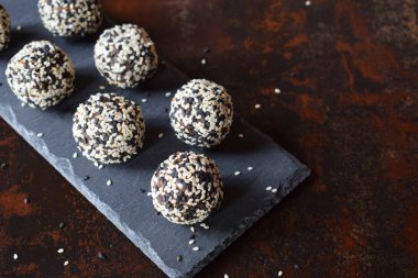 Sağlıklı ham enerji keten tohumu, badem, muz ve tarihleri ile ısırır. Vegan domalan susam koyu arka plan üzerinde içinde. Ev yapımı şeker topları. Çiğ gıda. Ücretsiz Gluten. Süt ücretsiz.