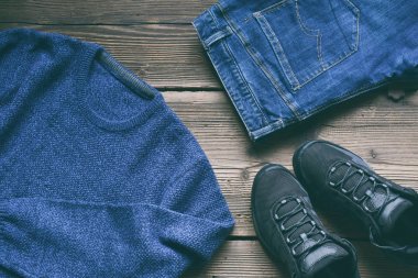 Erkekler gündelik kıyafeti. Erkek Ayakkabı, giyim ve Aksesuar ahşap arka plan - kazak, kot pantolon, spor ayakkabı. Üstten Görünüm. Düz yatıyordu