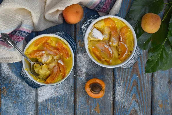 Clafouti rameken mavi ahşap zemin üzerine kayısı ile. Meyve clafoutis. Tatlı güveç. Geleneksel Fransız pasta. Kopya alanı