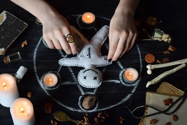 En la muñeca vudú hay agujas pinchadas. Velas, pentagramas, piedras, pociones de amor y libros antiguos sobre mesa de brujas. Concepto oculto, esotérico o adivinación. Mística, Halloween y fondo vintage — Foto de Stock