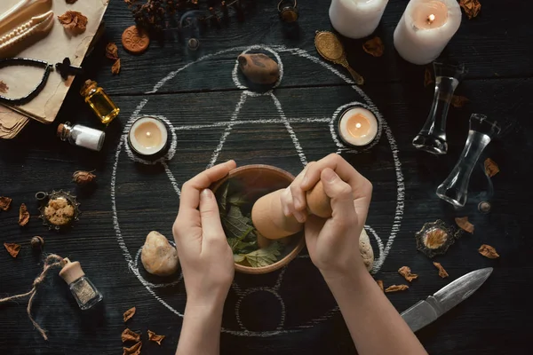 As mãos de mulheres fazem a poção de amor no círculo de pentagrama com velas, pedras e velhos livros na mesa de bruxas. Conceito oculto, esotérico ou de adivinhação. Místico, Halloween e fundo vintage — Fotografia de Stock