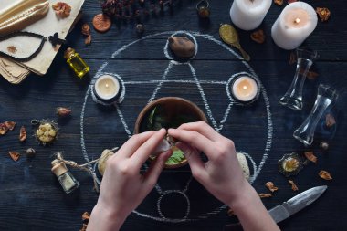 Kadın elleri mumlar, taşlar ve cadı masasında eski kitaplar ile pentagram daire üzerinde aşk iksiri yapmak. Gizli, ezoterik veya kehanet kavramı. Mistik, Cadılar Bayramı ve vintage arka plan