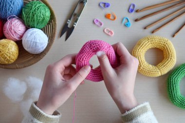 Renkli halkalardan tığ piramidi yapmak. Bebekler ve küçük çocuklar için oyuncak mekanik beceri ve renkleri öğrenmek için. Masanın iplikleri, iğneler, kanca, pamuk ipliği. El yapımı el sanatları. Diy kavramı.