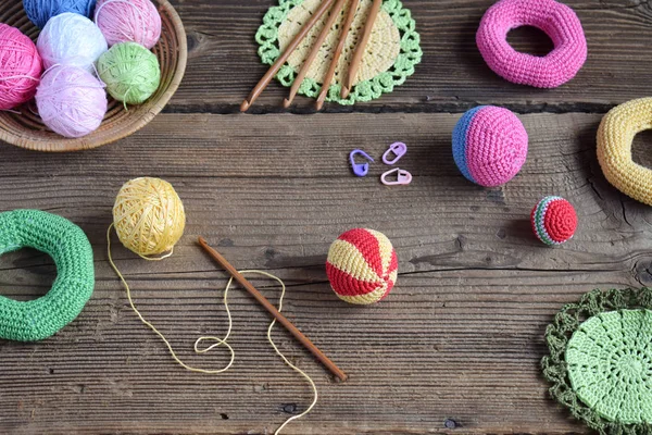 Making colored crochet balls. Toy for babies and toddlers to learn mechanical skills and colors. On the table threads, needles, hook, cotton yarn. Handmade crafts. DIY concept.