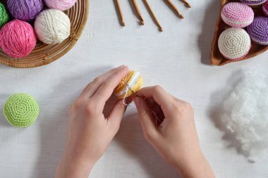 Tığ işi amigurumi Fransız badem kurabiyesi yapıyorum. Bebekler için oyuncak ya da incik boncuk. İplik, iğne, kanca, pamuk ipliği. El yapımı bir hediye. Hobiden gelir. DIY el işi konsepti. Üçüncü adım - tüm ayrıntıları dikmek.