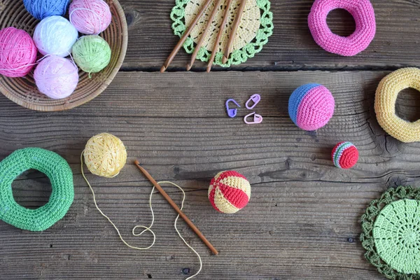 Making colored crochet balls. The toy for babies and toddlers to learn mechanical skills and colors. On the table threads, needles, hook, cotton yarn. Handmade crafts. DIY concept.