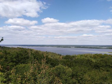 Dinyeper Nehri 'nin harika manzarası mavi gökyüzünün altındaki yeşil ağaçların arasından bulutlarla