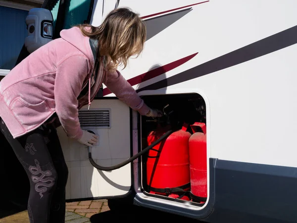 Bir bayan eğlence aracındaki bir dolapta gaz şişelerini kontrol ediyor.