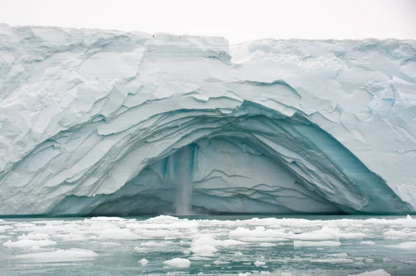 一段冰封的海堤裂开了 露出了瀑布 破碎的冰碎片在前方漂流 — 图库照片