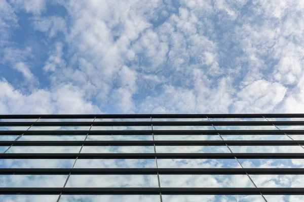 blue sky reflected in office window glass. office and business building. Blue sky with clouds
