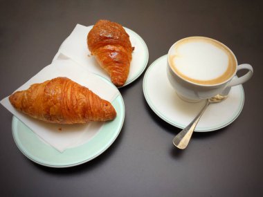 Kapuçino beyaz Kupası, kruvasan karanlık retro arka plan, seçici odak üzerinde. Kahvaltı konsepti