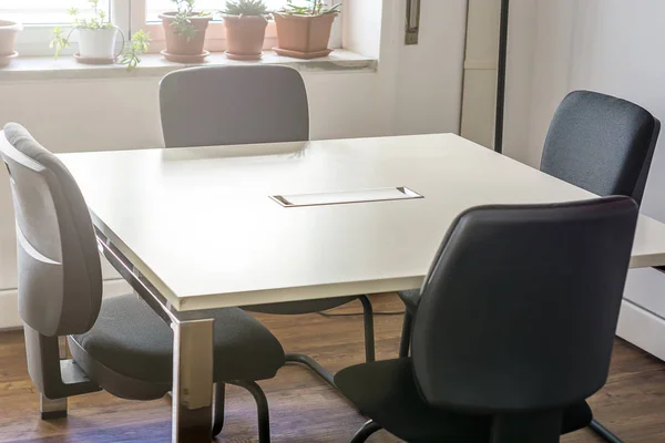 four empty chairs in a conference room with a white table