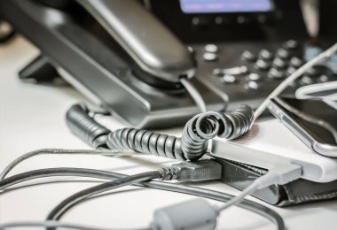 Bükülmüş telefon sarmal kablosu ve bir ofisteki diğer fişi takılı cihazlar