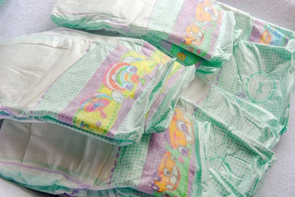 Group of disposable diapers arranged over a white changing table — Stock Photo, Image