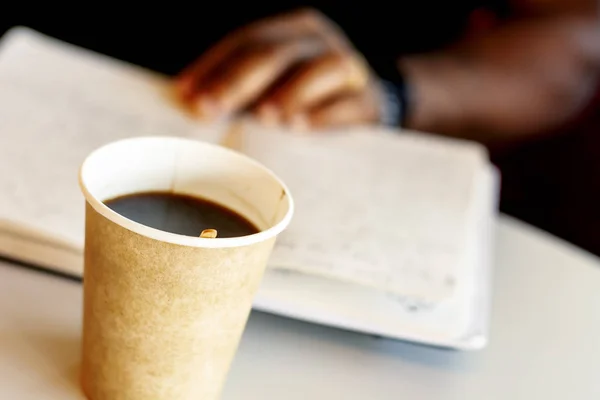 Uma caneca de café com um homem negro lendo um livro — Fotografia de Stock