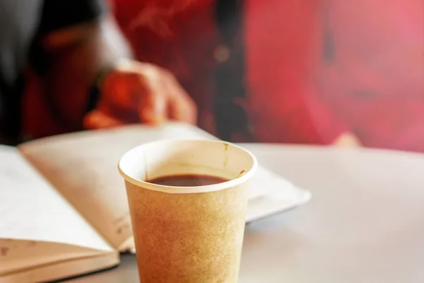 Kaffe i en återvunnen pappers behållare med personer som läser och kopplar av i den suddiga bakgrunden — Stockfoto