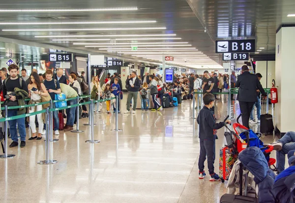 Multitud de personas esperando en fila para registrarse en un aeropuerto —  Fotos de Stock