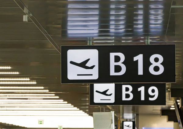Panel de información con el pictograma de un avión despegando para indicar la puerta de embarque B 18 dentro de un aeropuerto —  Fotos de Stock