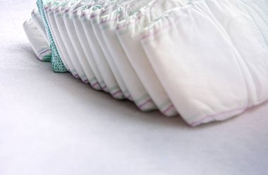 Bir grup tek kullanımlık bebek bezi beyaz bir masanın üzerine yerleştirilmiş.