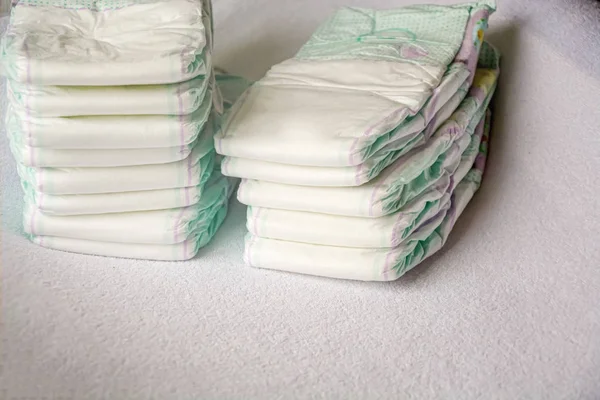 Group of disposable diapers arranged over a white changing table — Stock Photo, Image