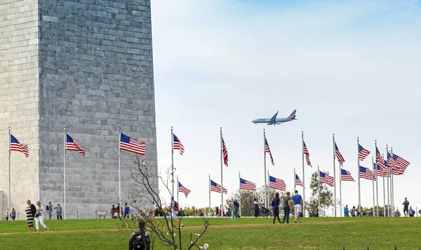 People visiting the Washington Monument with a commercial airplane landing in the background — Stock Photo, Image