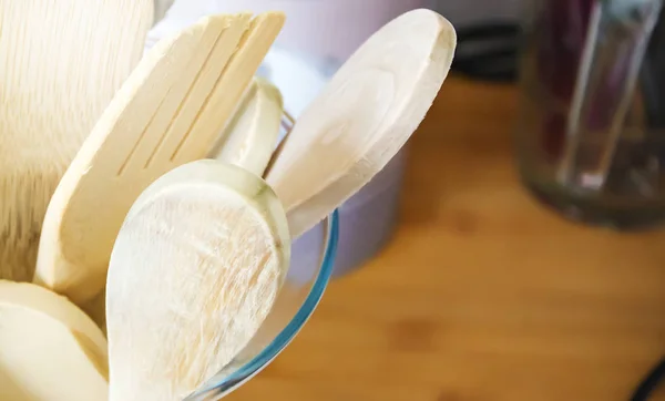 Close-up view of a group of wooden kitchen utensils inside a glass container.