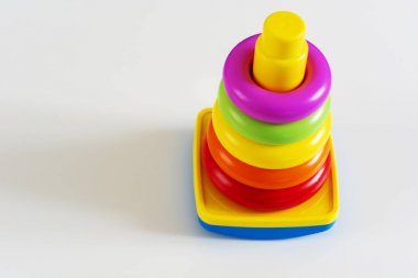 Çeşitli renklerde plastik halkalar sarı plastik kule yığılmış.