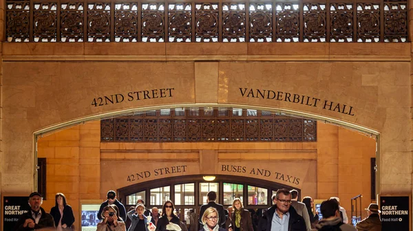 Personas caminando bajo el arco con indicaciones a Vanderbilt Hall y la calle 42 dentro de la Grand Central Station de Nueva York — Foto de Stock