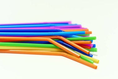 Beyaz arkaplanda çeşitli renklerde plastik pipetler grubu.