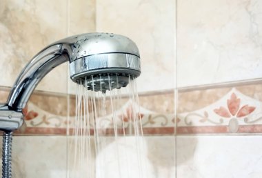 Duş başlığından su akan bir duşun içinde. Damlacıklar ve nem. Süslü fayanslı duvarlar. Hijyen ve kişisel bakım