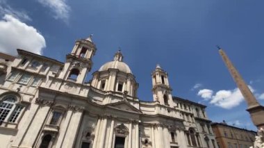 Düşük açılı kamera Sant 'Agnese Kilisesi cephesinden Roma' daki Piazza Navona Meydanı 'nın merkezindeki Dört Nehir Çeşmesine doğru dönüyor.