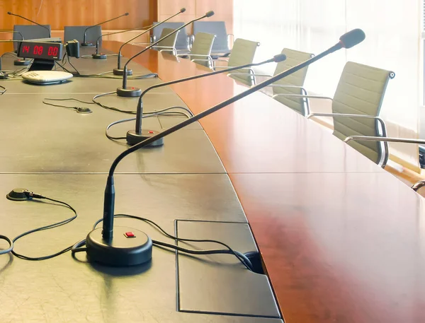 Microphone on a wooden table and empty chairs in a boardroom. Auditorium, meeting.