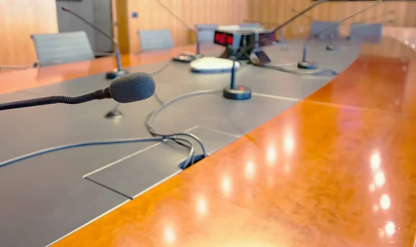 Microphone on a wooden table and empty chairs in a boardroom. Auditorium, meeting.
