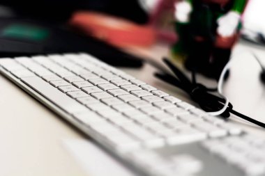 Ofis masasında beyaz tuşları olan modern gri bir bilgisayar klavyesi. Yüzeyin derinliği. Meslek ve ofis işi