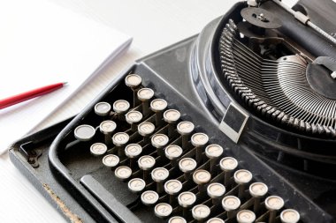 Kırmızı kalemli beyaz bir kağıt parçasının yanında eski siyah bir daktilo. Gazetecilik ve yazma araçları. Hikaye anlatma ve yaratıcı etkinlik