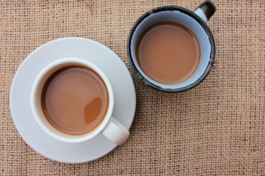 İki fincan sütlü kahve ya da çuval bezi desenli kapuçino. Sabah kahvesinin tadını çıkarıyorum. Üst görünüm, boşluğu kopyala. Seçici odak