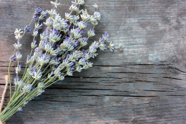 Gri aşınmış ahşap arka planda bir demet lavanta çiçeği. Yakın çekim, üst görünüm, seçici odak