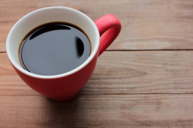 Ahşap masa arkasında fotokopi alanı olan kırmızı bir fincan kahve. Üst Manzara. Seçici odak