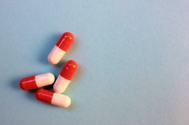 Kırmızı ve beyaz haplar veya mavi arka planda fotokopi alanı olan kapsüller. Üst görünüm, seçici odak