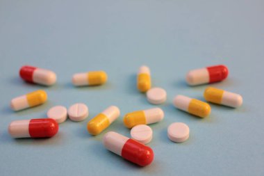 Çok renkli haplar ve kapsüller mavi arka planda fotokopi alanı ile. Üst görünüm, seçici odak