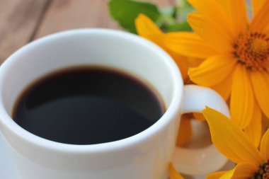 Kahve ve ahşap masanın üzerindeki sarı çiçeklerden. Yaz yaşam tarzı