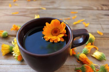 Bitkisel detoks calendula çayı, ahşap arka planda taze çiçekler ve fotokopi alanı. Üst görünüm